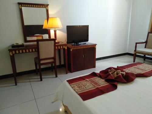 a bedroom with a bed and a tv and chairs at Excelsior Resort in Dili