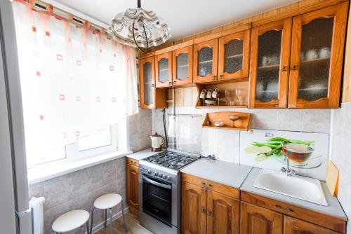a kitchen with wooden cabinets and a stove at Квартира на Козлова 13 in Salihorsk