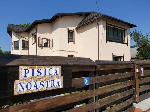 a house behind a fence with a sign on it at Casa Pisica Noastra in Breaza