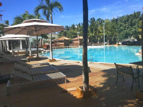 a large swimming pool with chairs and an umbrella at 皇家一号度假村 Tourist Garden Hotel in Mactan