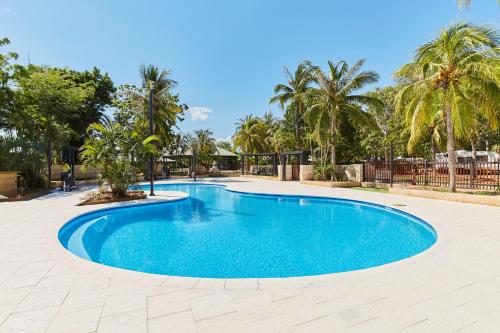 a large blue swimming pool in a yard with palm trees at RAC Cable Beach Holiday Park in Broome