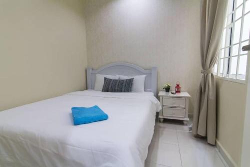 ein Schlafzimmer mit einem weißen Bett und einem blauen Kissen darauf in der Unterkunft MELAKA HOMESTAY in Malakka