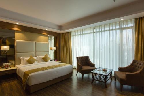 a hotel room with a bed and two chairs at Sarovar Portico, Somnath in Somnath