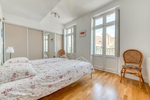 une chambre blanche avec un lit et une chaise dans l'établissement Les Clés de Laure - Wine Loft, Terrasse et Vue extraordinaire sur la cité médiévale, à Carcassonne