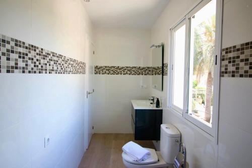 a bathroom with a toilet and a sink and a window at Els Poblets WD by CARLOSFERIEN in Els Poblets
