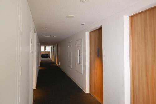 a hallway with white walls and a long hallway with doors at Hotel Relief Kokura Annex in Kitakyushu
