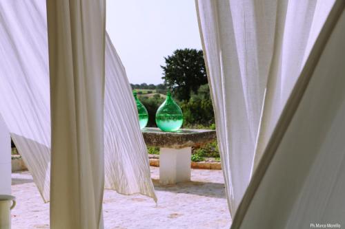 two green vases sitting on a table with curtains at Tenuta del Lauro in Locorotondo