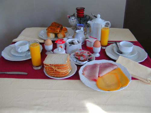 a breakfast table with breakfast foods and orange juice at B&B Le Petit Normand in Jalhay