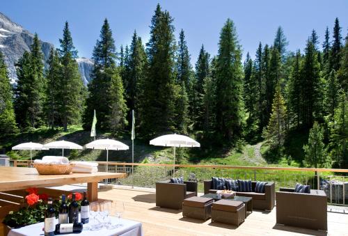 a patio with couches and umbrellas on a deck at Hotel Sella***s in Selva di Val Gardena