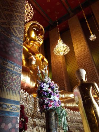 a gold statue in a room with flowers next to it at Stash in Bangkok