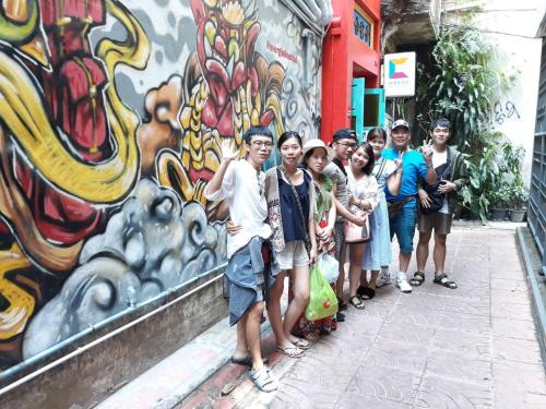 a group of people standing in front of a graffiti wall at Stash in Bangkok