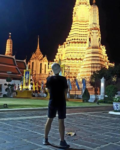 a man taking a picture of a temple at night at Stash in Bangkok