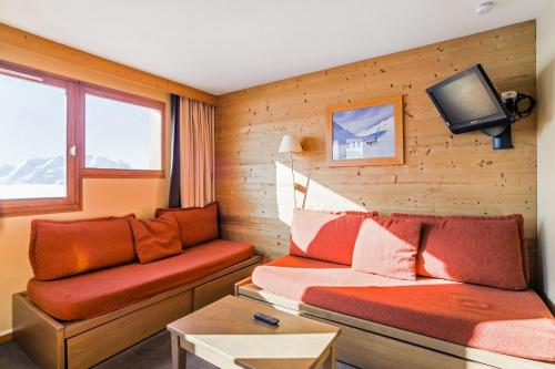 Cette chambre dispose d'un canapé et d'une télévision murale. dans l'établissement Residence L'Ours Blanc - maeva Home, à L'Alpe-d'Huez