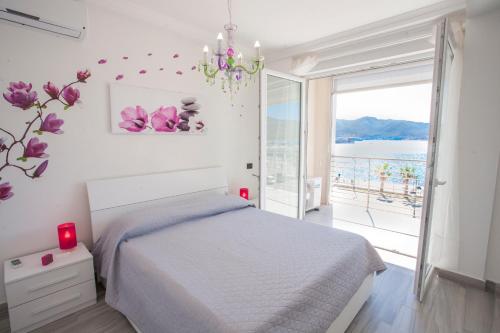 a white bedroom with a bed and a large window at Appartamenti Lungomare Portoferraio - Goelba in Portoferraio