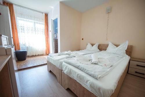 a large white bed in a room with a window at COMPLEX Alutus -Camere de inchiriat in Mangalia
