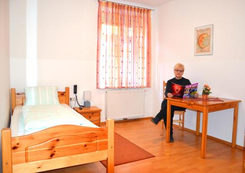 a woman sitting at a desk in a bedroom at Gasthof zum Goldenen Pflug in Amstetten