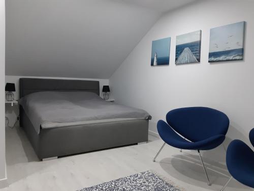 a bedroom with a bed and a blue chair at Apartamenty Platinum 2 in Łukęcin
