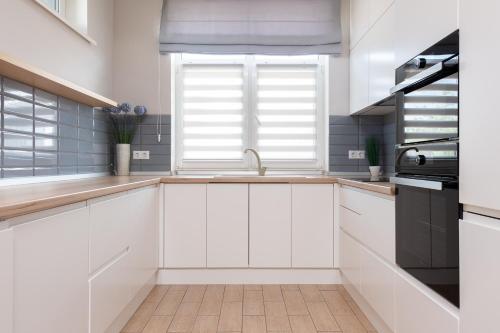 a white kitchen with a sink and a window at Riviera Zoloche Resort & Spa in Vishenki