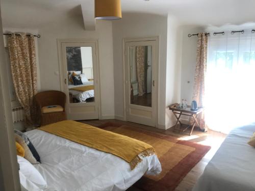 a bedroom with a bed and two windows and a mirror at Les Chênes in Bénesse-Maremne