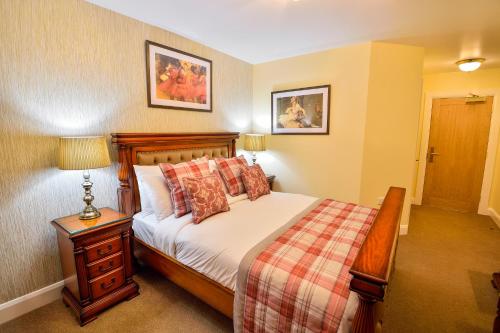 a bedroom with a bed and a table with a lamp at The George Hotel in Axminster
