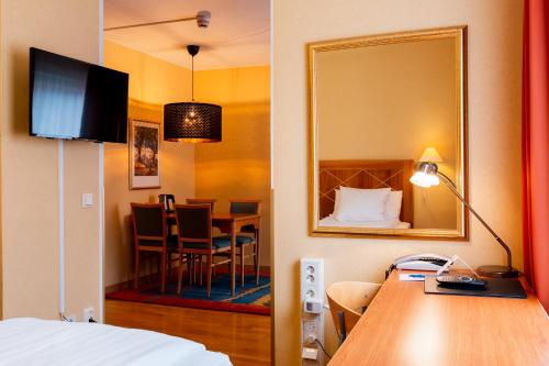 a room with a bed and a table and a mirror at Best Western Hotel Esplanade in Västerås