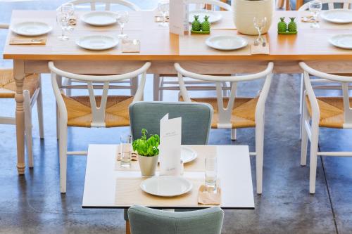 a table in a restaurant with white plates and chairs at Hotel Kriopigi in Kriopigi