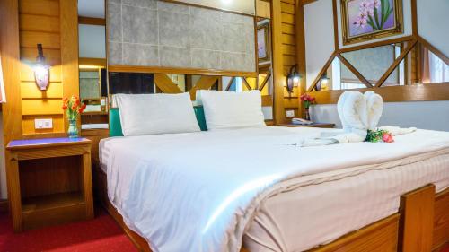 a bedroom with a large bed with white sheets at โรงแรมศิริโฮเต็ล Sirihotel Korat in Nakhon Ratchasima