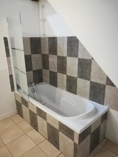 a bath tub in a bathroom with a checkerboard wall at Manoir de Bolbec in Bolbec