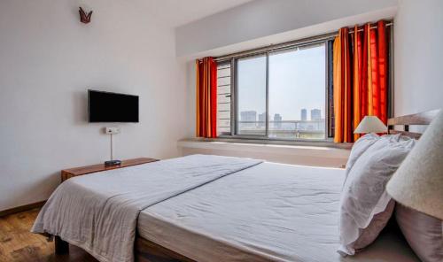 1 dormitorio con cama y ventana grande en Isec Apartment, en Bombay