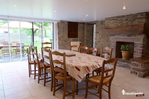 een eetkamer met een tafel en stoelen en een open haard bij Gite Lancelot du Val in Campénéac