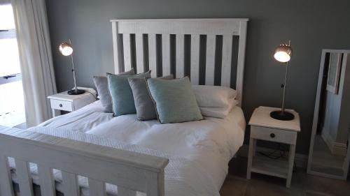 1 dormitorio con 1 cama blanca con almohadas y 2 lámparas en Waterside Living CAN05, en Jeffreys Bay