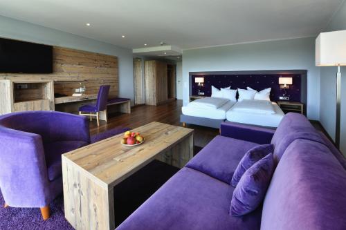 a hotel room with a bed and a purple couch at Hotel Rebenhof in Baden-Baden