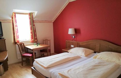 a bedroom with two beds and a red wall at Gasthof Pichler in Grimmenstein