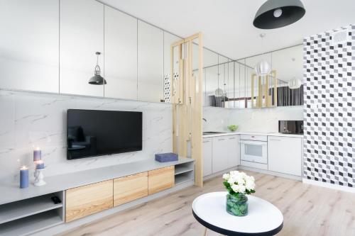 a white living room with a tv and a table at Elite Apartments SPA Zone in Gdańsk