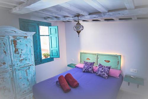 a bedroom with a blue bed with colorful pillows at Riad Puertas del Albaicín in Granada