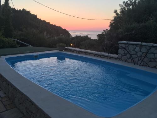 una piscina blu con tramonto sullo sfondo di Villa Christianna Studios a Ayios Nikitas