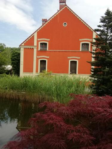 a red building next to a body of water at Dworek 1885 in Ostrzeszów