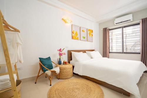 a white bedroom with a bed and a chair at Centre Alley House & Travel in Hanoi