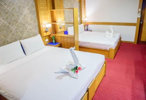 a hotel room with two beds with a flower bouquet at โรงแรมศิริโฮเต็ล Sirihotel Korat in Nakhon Ratchasima