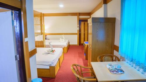 a room with two beds and a table and chairs at โรงแรมศิริโฮเต็ล Sirihotel Korat in Nakhon Ratchasima