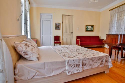 a bedroom with a bed with a red couch and a piano at Pospolita Guest House in Kutaisi
