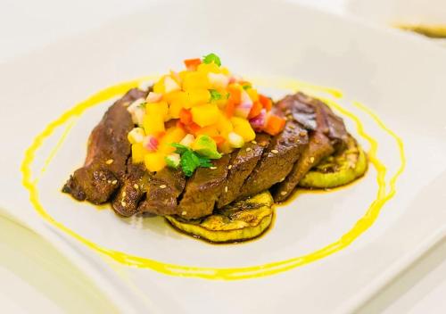 a white plate with a steak with vegetables on it at Luks Lofts Hotel & Residences in Batangas City