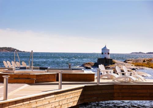 a dock with chairs and a lighthouse in the water at Nynäs Havsbad in Nynäshamn
