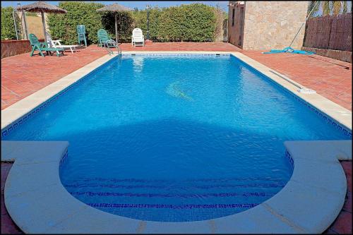 duży niebieski basen z 2 krzesłami i stołem w obiekcie Apartamento con piscina comunitaria w mieście Conil de la Frontera