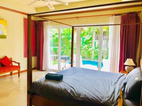 um quarto com uma cama e uma grande janela em Karon Pool Villa 卡伦3卧泳池别墅 em Praia de Karon