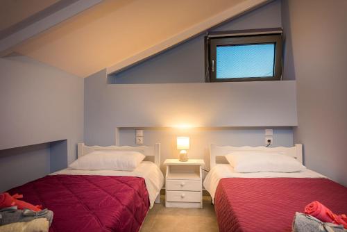two beds in a small room with a window at Vizantida Maisonette, By TK Property Management in Zakynthos Town