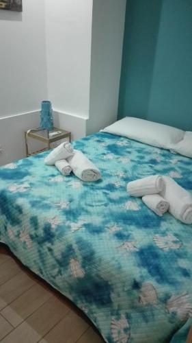 a bed with a blue comforter with towels on it at Smile's Home in Catania