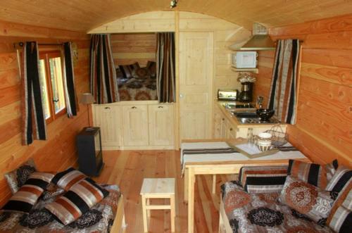 - une cuisine avec un canapé et une table dans une cabine dans l'établissement Roulotte de Dilou Noisette, à Matha