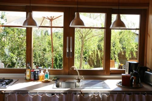 uma cozinha com 2 janelas e um lavatório. em Chambres "Au Jardin" em Biscarrosse