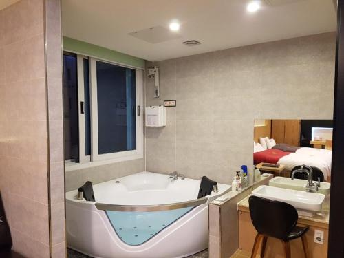 a bathroom with a tub and a sink and a bed at No.1 New Yorker Hotel in Jinju